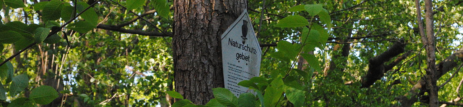 Ein Schild an einem Baum, das auf ein Naturschutzgebiet hinweist.